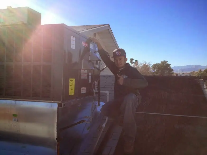 HVAC technician performing AC Tune-Up on a rooftop unit in Grosse Pointe